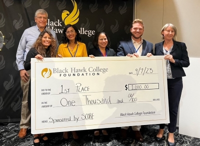 6 people standing and holding an oversized check for $1,000