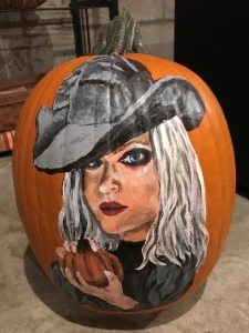 painted pumpkin with long-haired woman wearing hat & holding small pumpkin