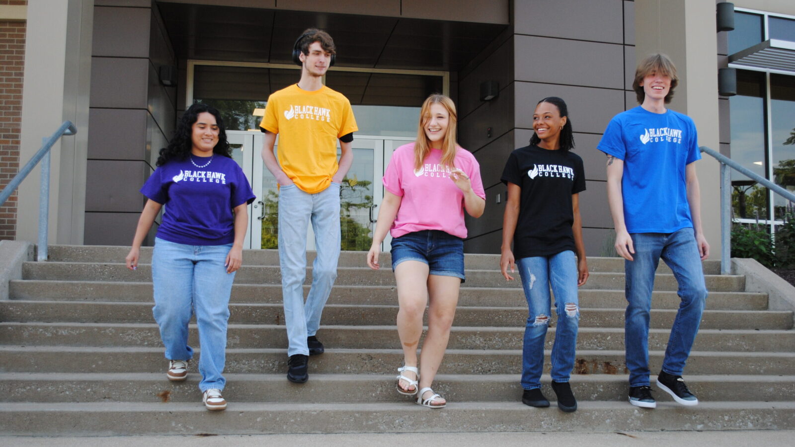 Five students walk down the stairs outside Black Hawk College.