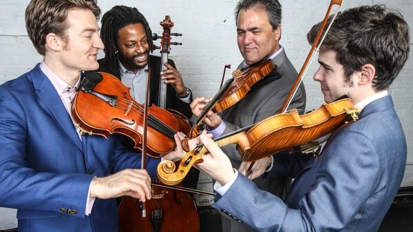 4 male musicians playing string instruments