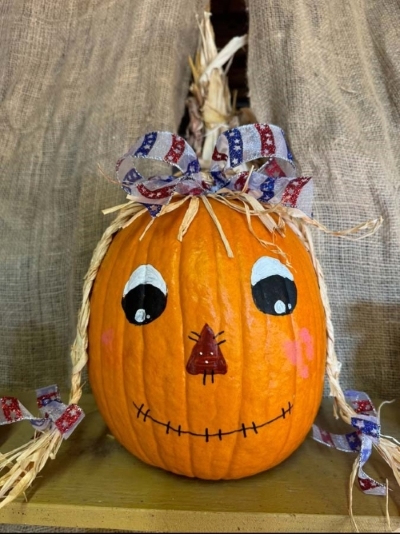 pumpkin painted to look like scarecrow with pigtails