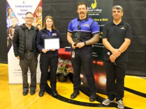 4 people standing in front of pull-up banners and one holding award certificate 