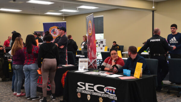 Students visit with a uniformed man at an event for Criminal Justice career exploration.