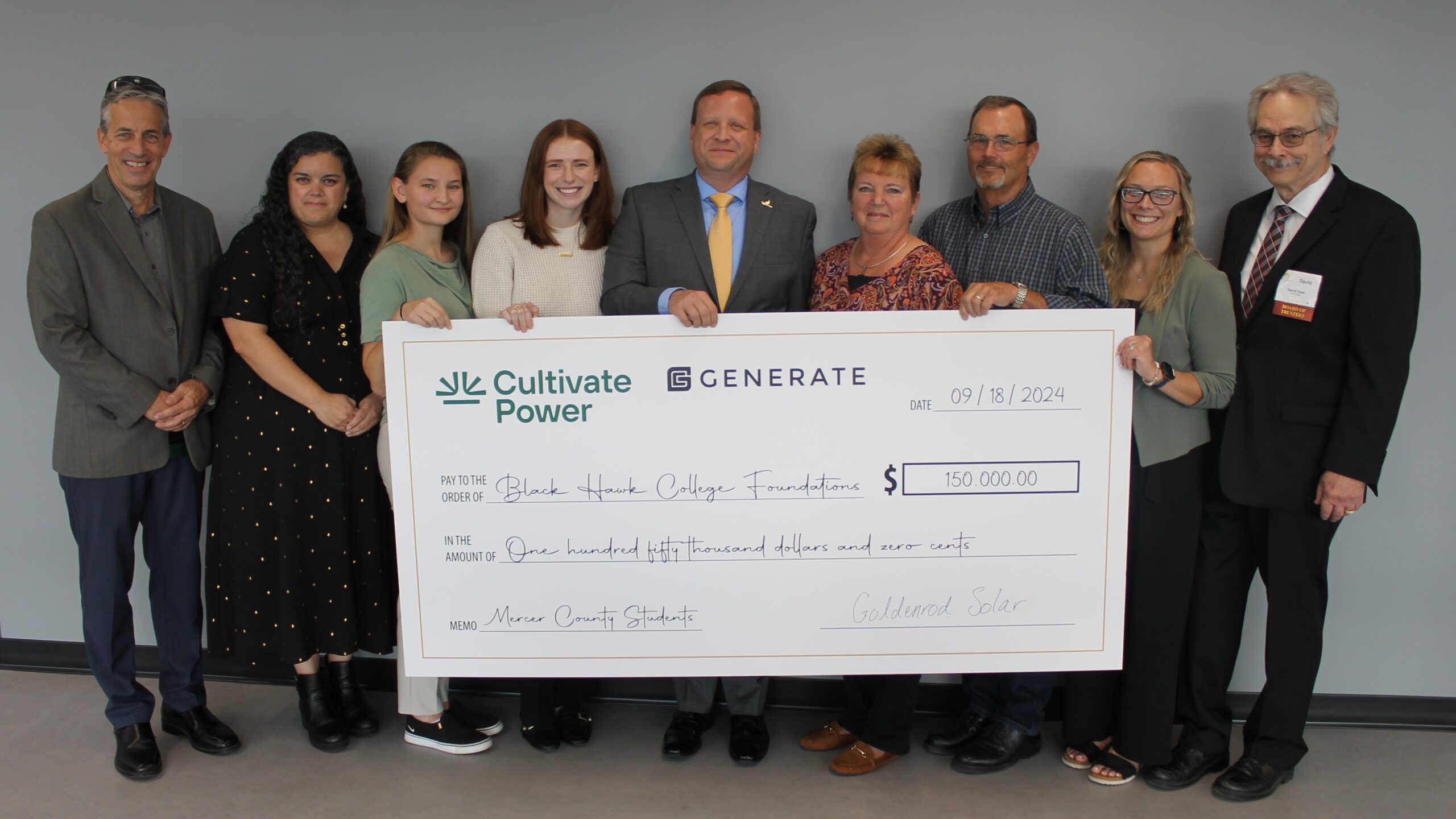 9 people smiling and holding an oversized check