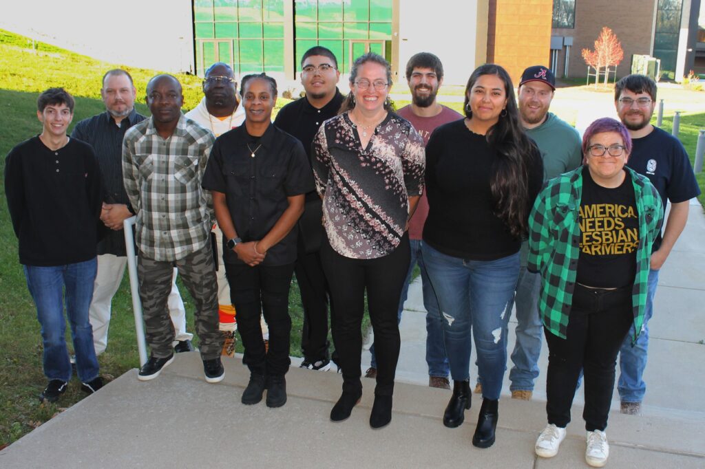 12 people standing outdoors and smiling at camera