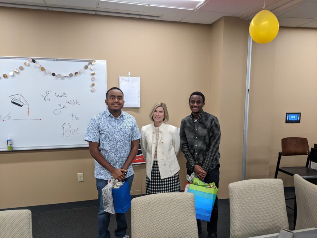 Afley Barnabas (left) and Christian Manzi (right) pictured with Becca Wynes at a farewell party.