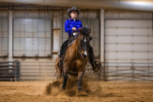 Western equestrian rider on horse kicking up dirt