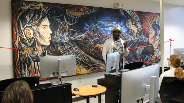 Terrance Gray standing in front of mural in electronic music classroom