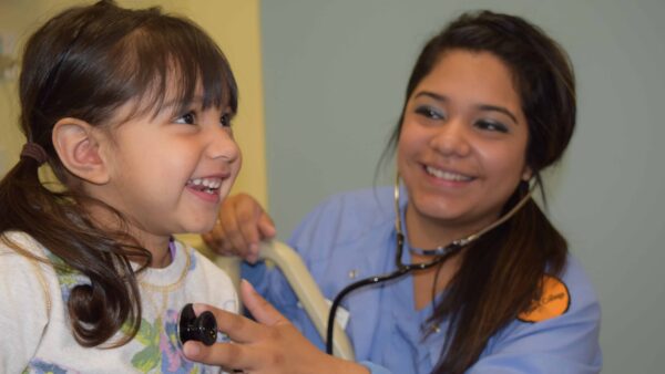 Female nursing student listening to child's heartbeat