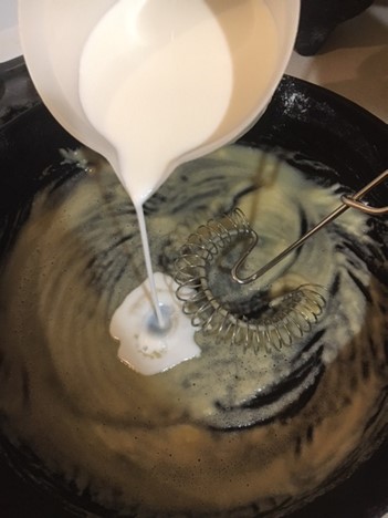 Slowly pouring milk into pan.