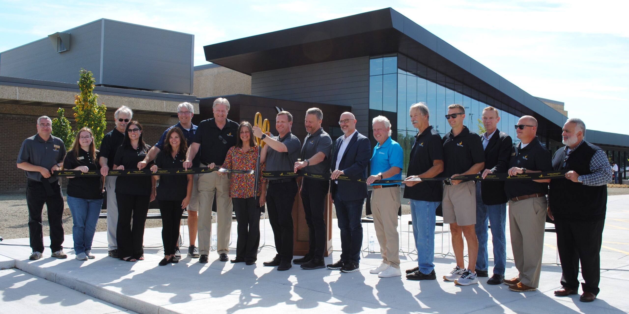 17 people holding ribbon outside Building 3 for ribbon cutting