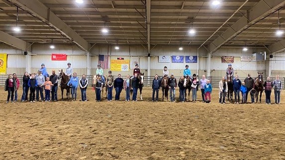 young riders sitting on horses in arena