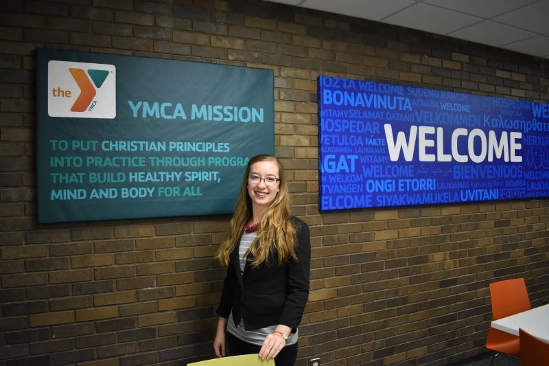 woman in front of brick wall with YMCA mission and welcome signs