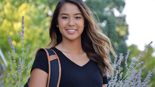 smiling student with flowers and trees in the background