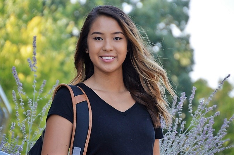 smiling student with flowers and trees in the background