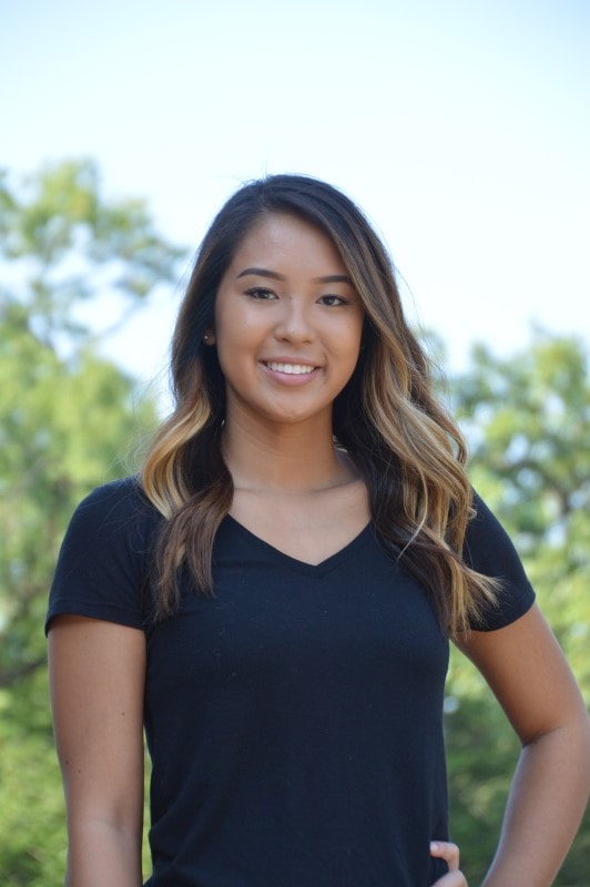 female student standing with trees in the background