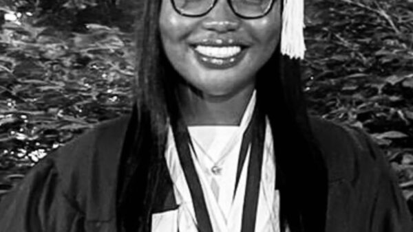 smiling student wearing cap & gown with awards & medals