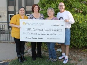 4 people standing outdoors holding oversized check