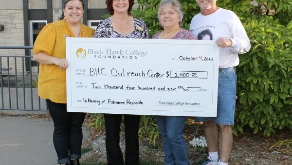 4 people standing outdoors holding oversized check