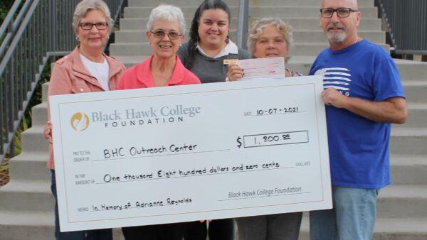 5 people standing outside Outreach Center with oversized check