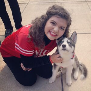 smiling student sitting with a husky puppy