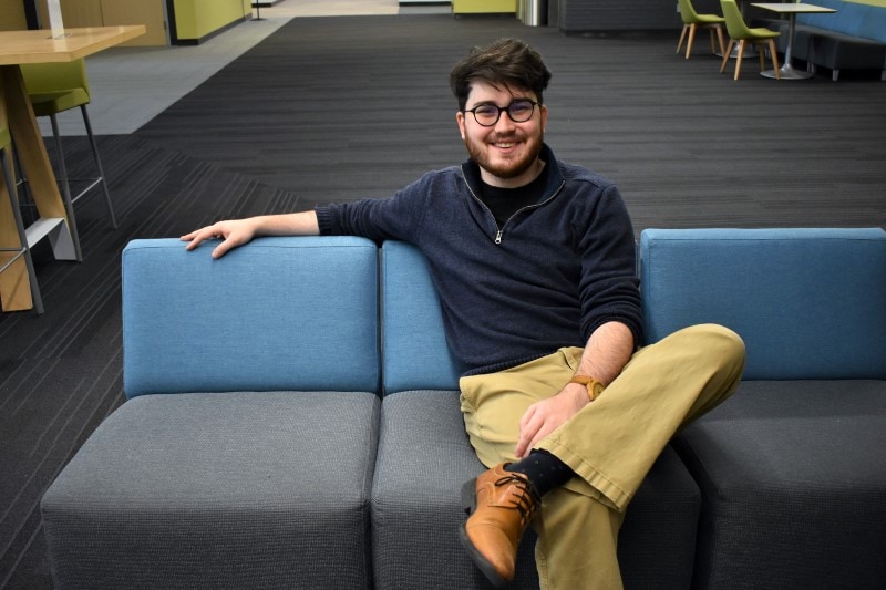 man sitting on couch in a lobby at Black Hawk College