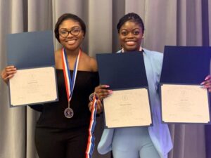 2 smiling students holding certificates