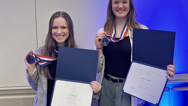 2 smiling students holding award medals and certificates