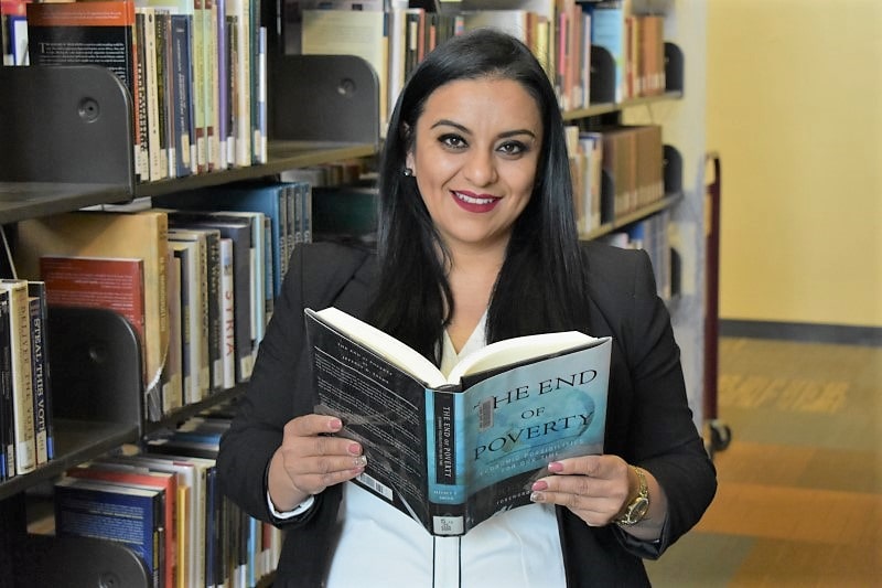 student holding open book in library