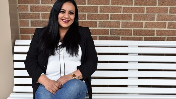 student sitting on a white bench against a brick wall