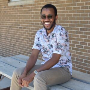 Smiling BHC graduate sitting on picnic table