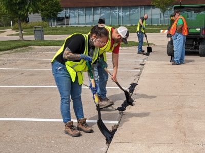 highway construction students filling potholes in parking lot on campus