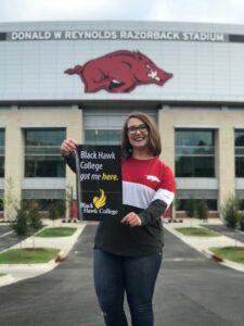 Student at University of Arkansas holding sign that says Black Hawk College got me here