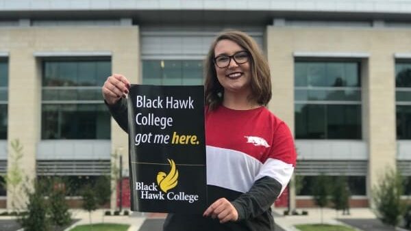 student holding BHC sign standing in front of a stadium