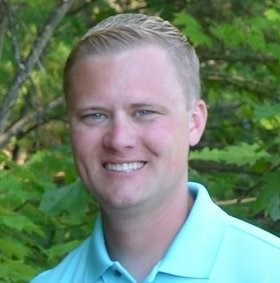 man smiling with greenery in the background