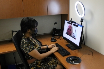 woman wearing mask at desk with computer & ring light