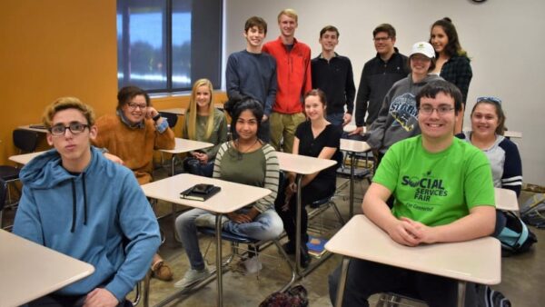 Black Hawk College Children's Literature students sitting at desks and standing in a classroom