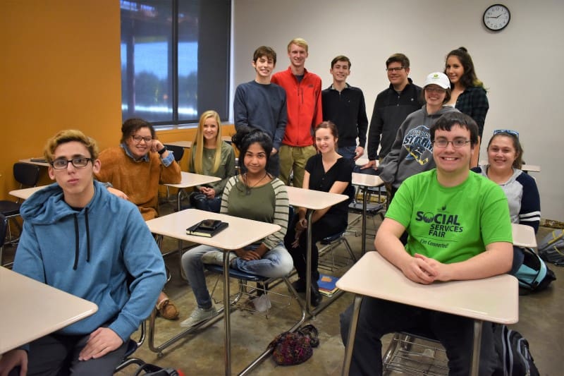 Black Hawk College Children's Literature students sitting at desks and standing in a classroom