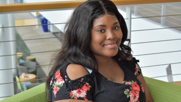 student sitting in a green chair in front of railing