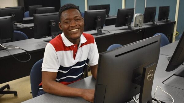 smiling male student sitting at a computer desk