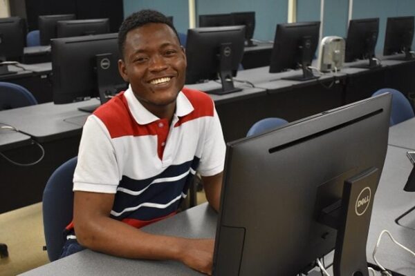 smiling male student sitting at a computer desk