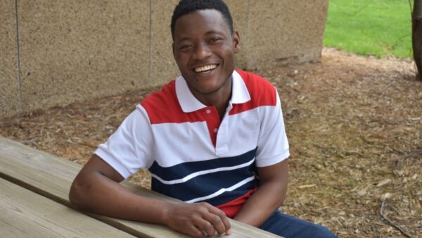 student sitting at a picnic table smiling