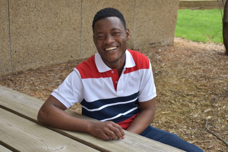 student sitting at a picnic table smiling