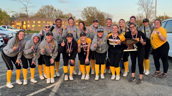 Softball players and coaches smiling at camera with Arrowhead Conference Championship trophy & medals