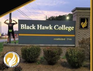 woman standing on the Black Hawk College sign during the Hawk Hustle event