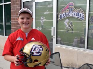 boy in red shirt holding QC gold football helmet