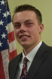 Head & shoulders shot of Dillon Sheiss with American flag in background