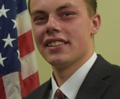 Head & shoulders shot of Dillon Sheiss with American flag in background