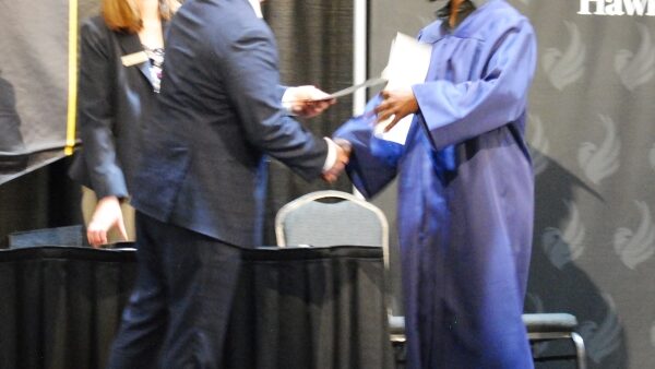 BHC president Dr. Jeremy Thomas handing certificate to GED grad Tony Johnson on stage