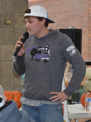 livestock judging team member with microphone and pumpkins on table in background